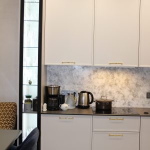 Стильная угловая кухня с пеналами и подсвеченными витринами в современной класике и столешницей HPL