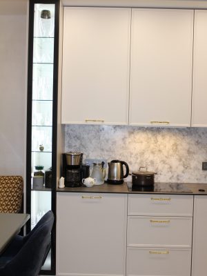 Стильная угловая кухня с пеналами и подсвеченными витринами в современной класике и столешницей HPL